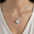 Silver heart-shaped pendant necklace on a model wearing a white top.