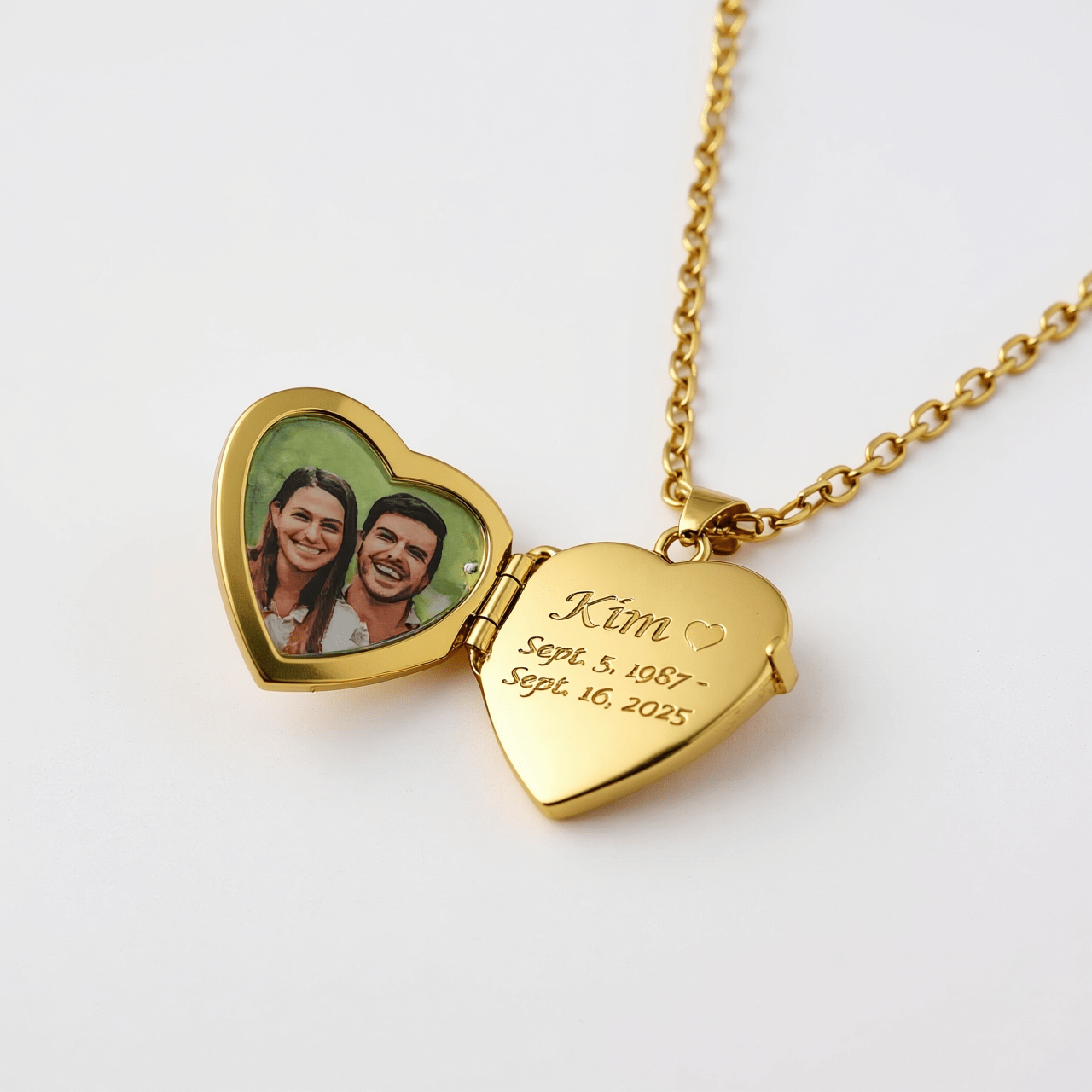 Gold heart-shaped locket open view with engraved name and dates, featuring a photo of a couple on a white background.